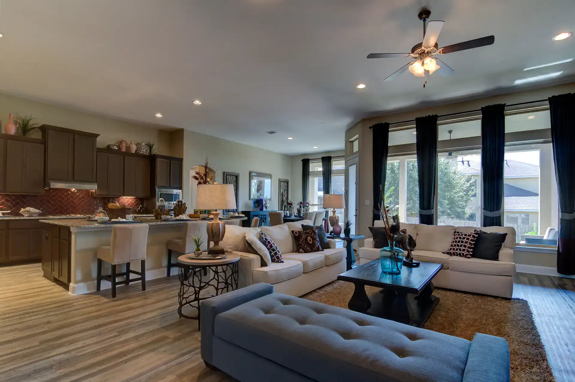 Modern living room with open kitchen and large windows.