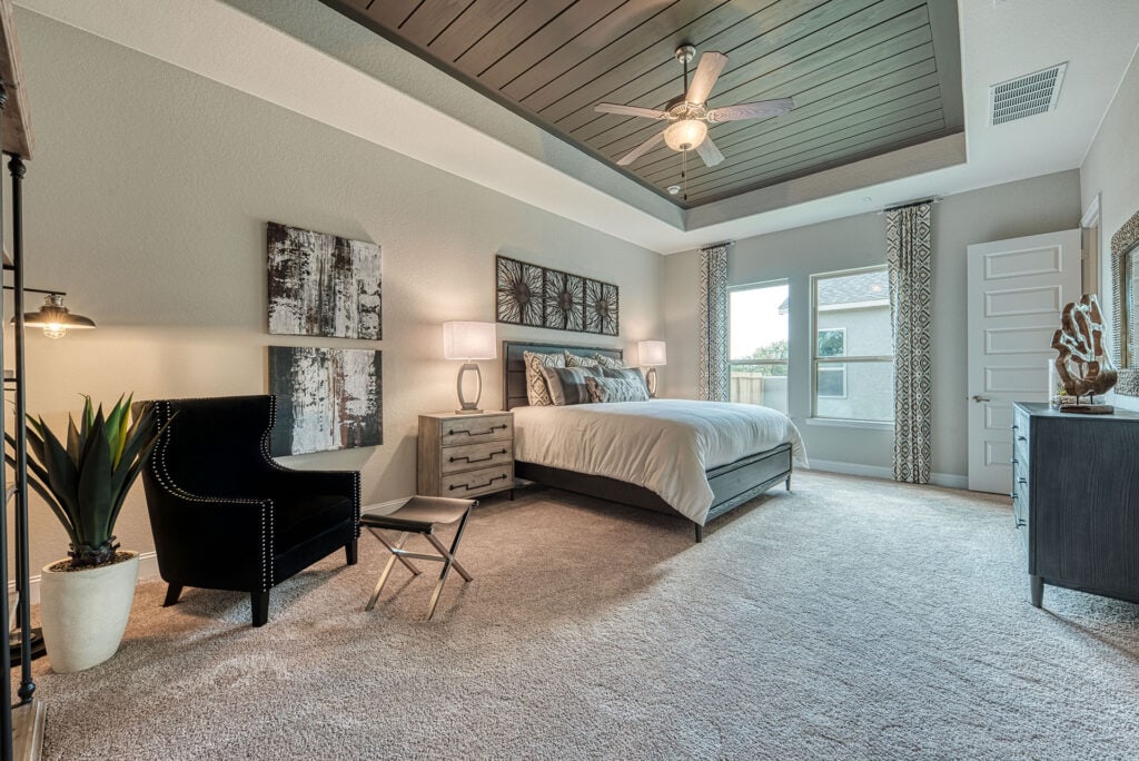 Modern bedroom with cozy decor and large windows.
