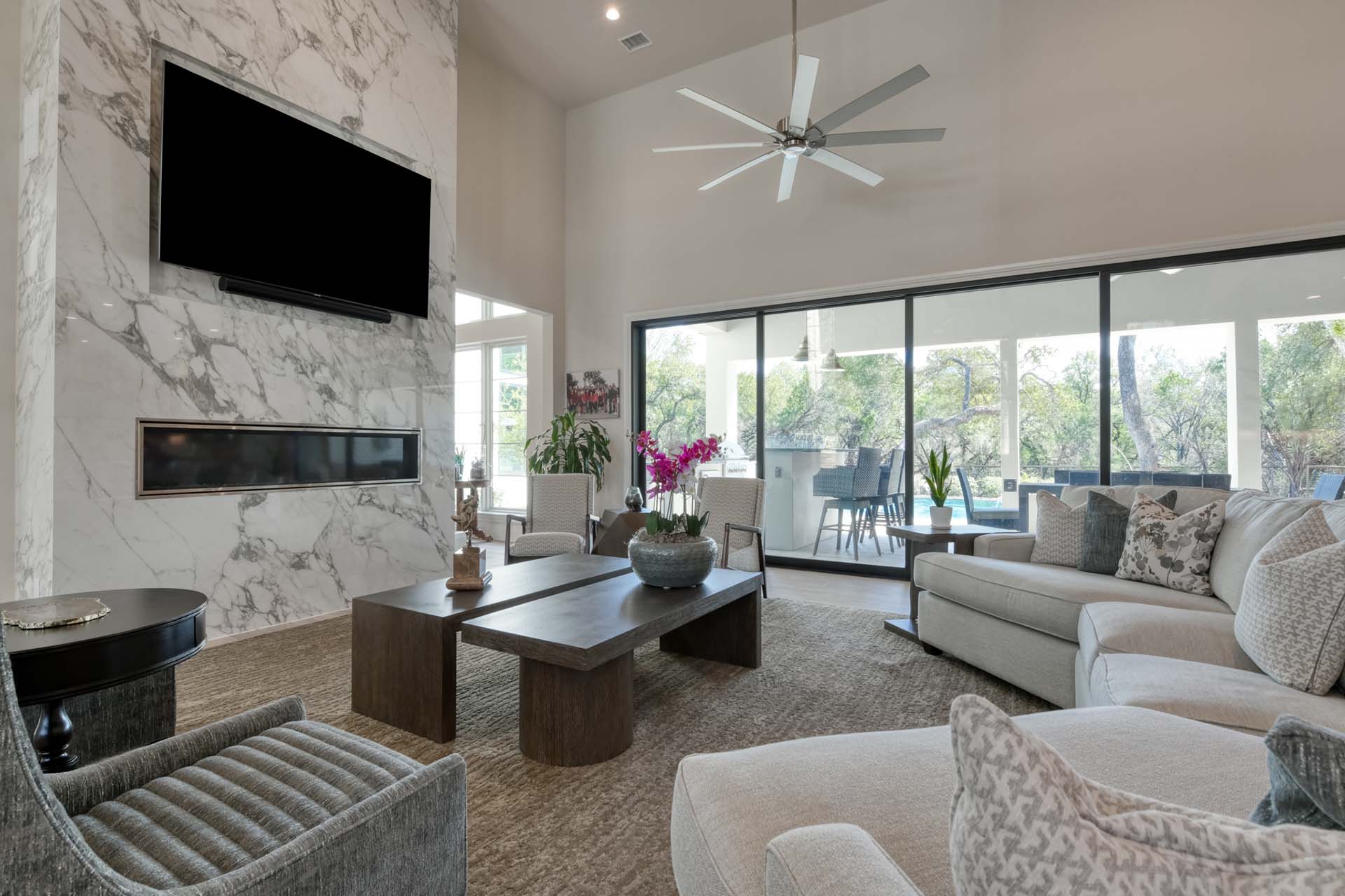 Modern living room with large windows and marble fireplace.
