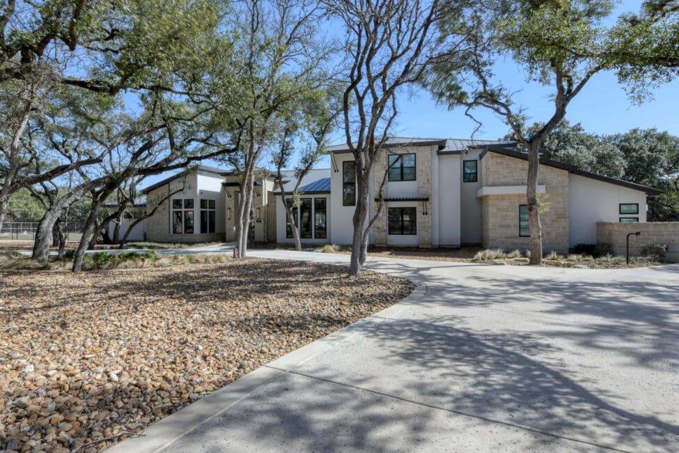 Modern house exterior with trees and pebble landscaping.