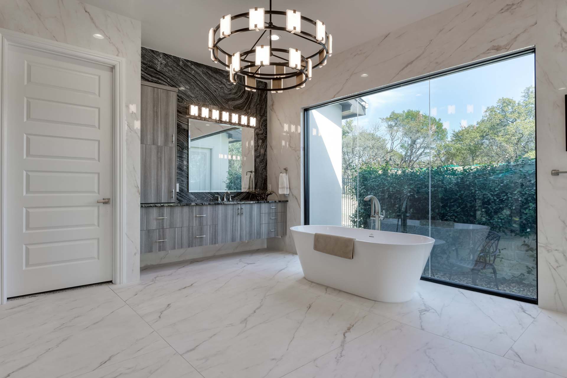 Modern bathroom with freestanding tub and large window.