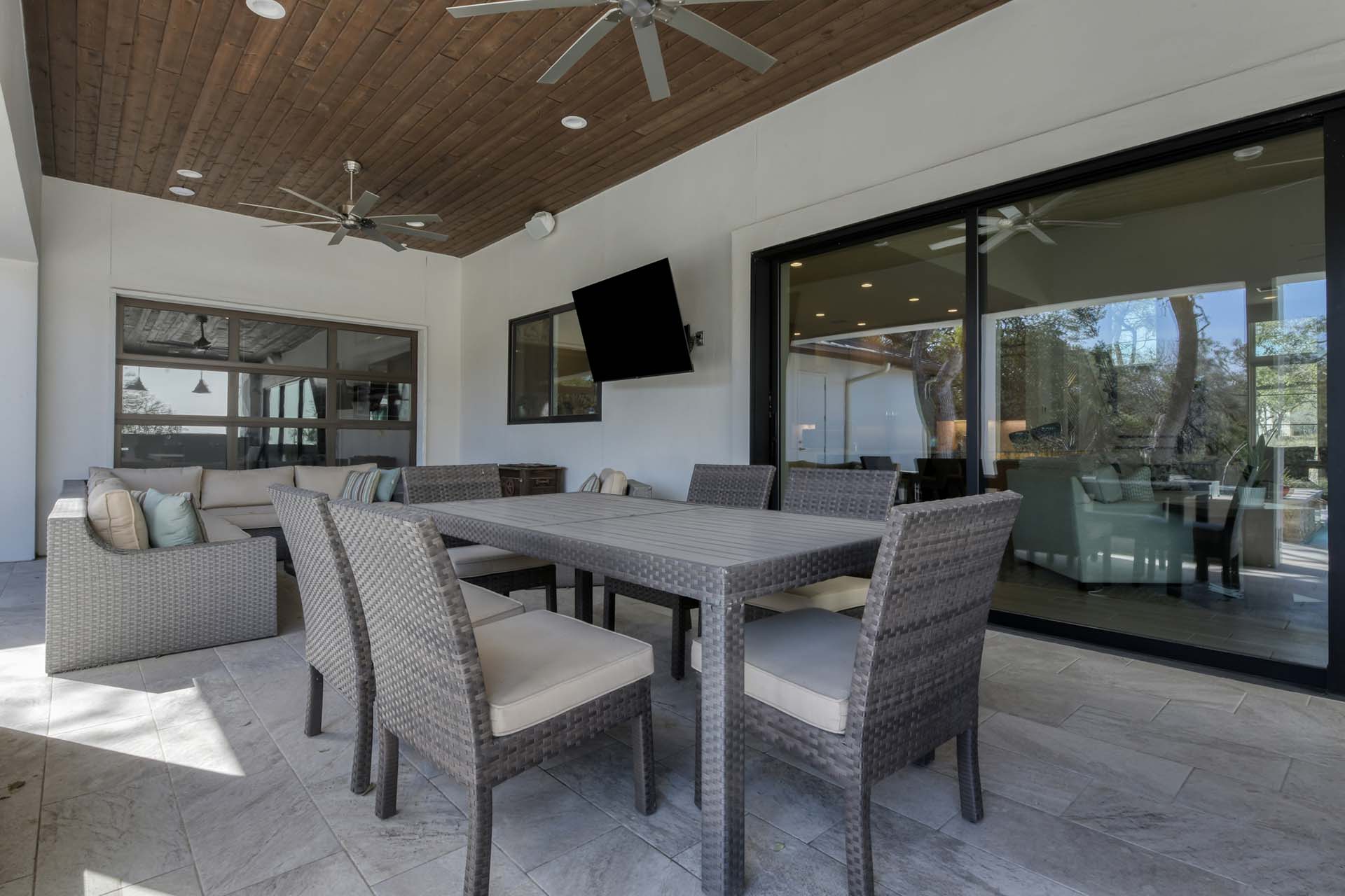 Outdoor patio with wicker dining set and ceiling fans.