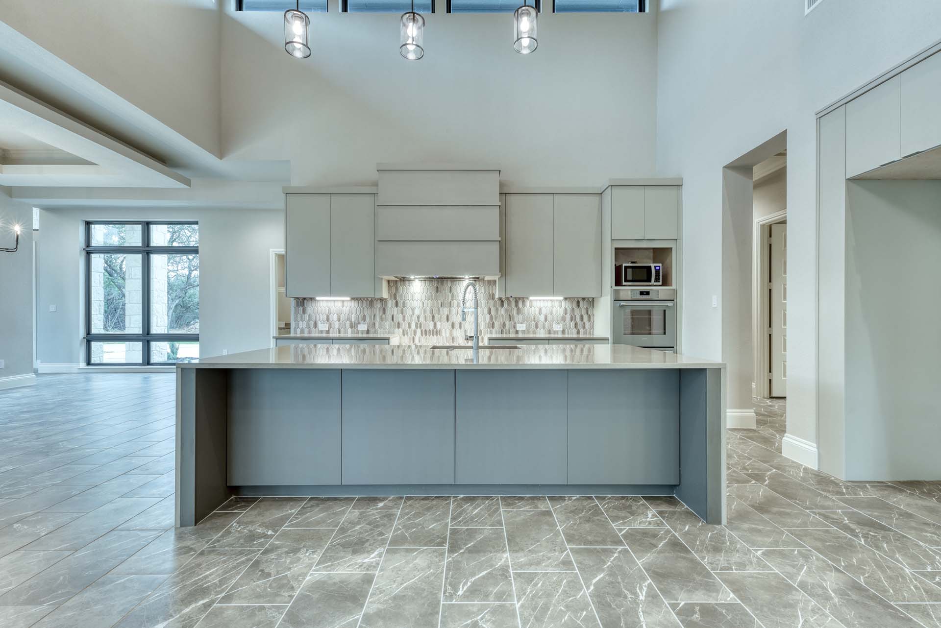 Modern kitchen with large island and tile flooring.