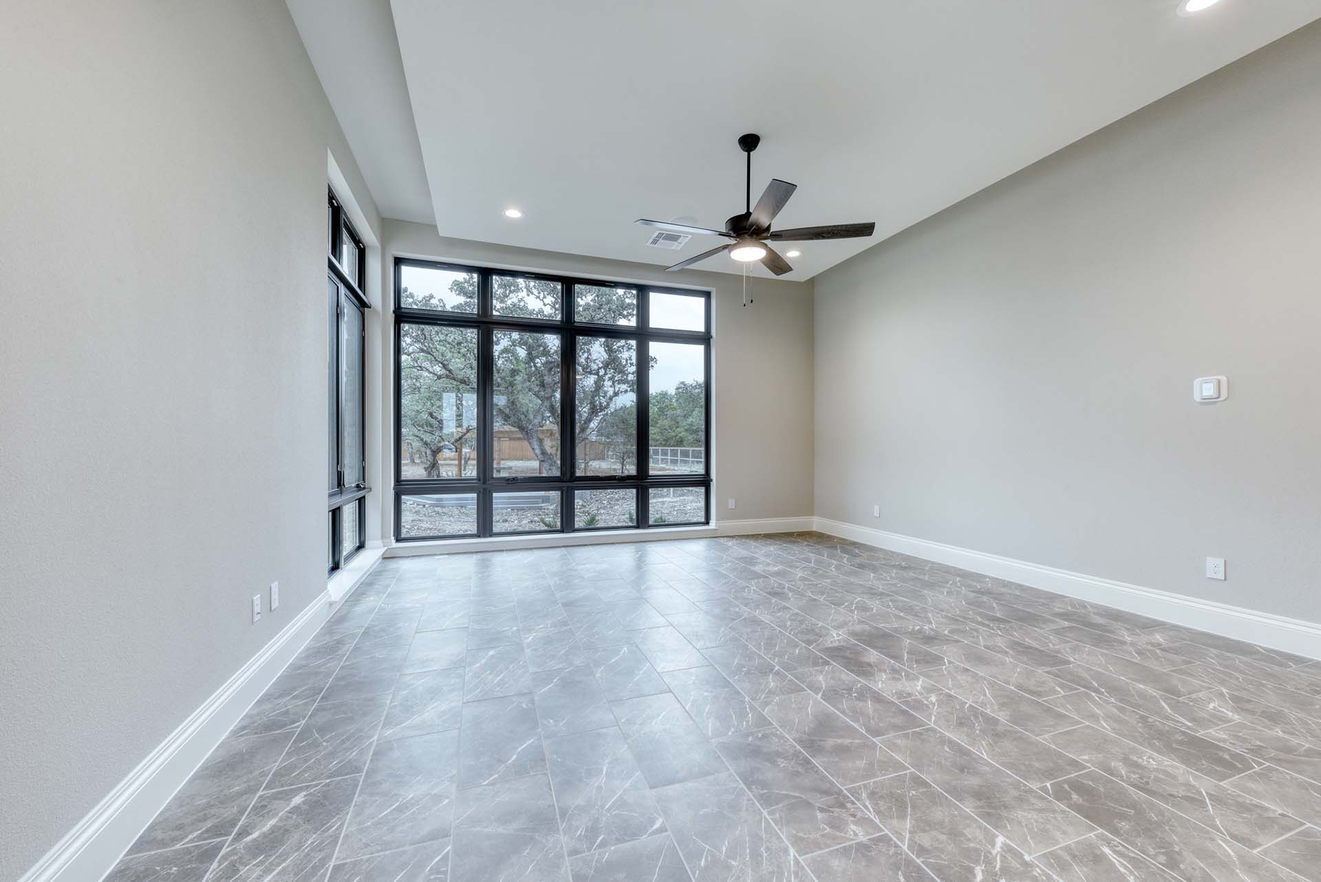 Spacious room with large windows and ceiling fan.