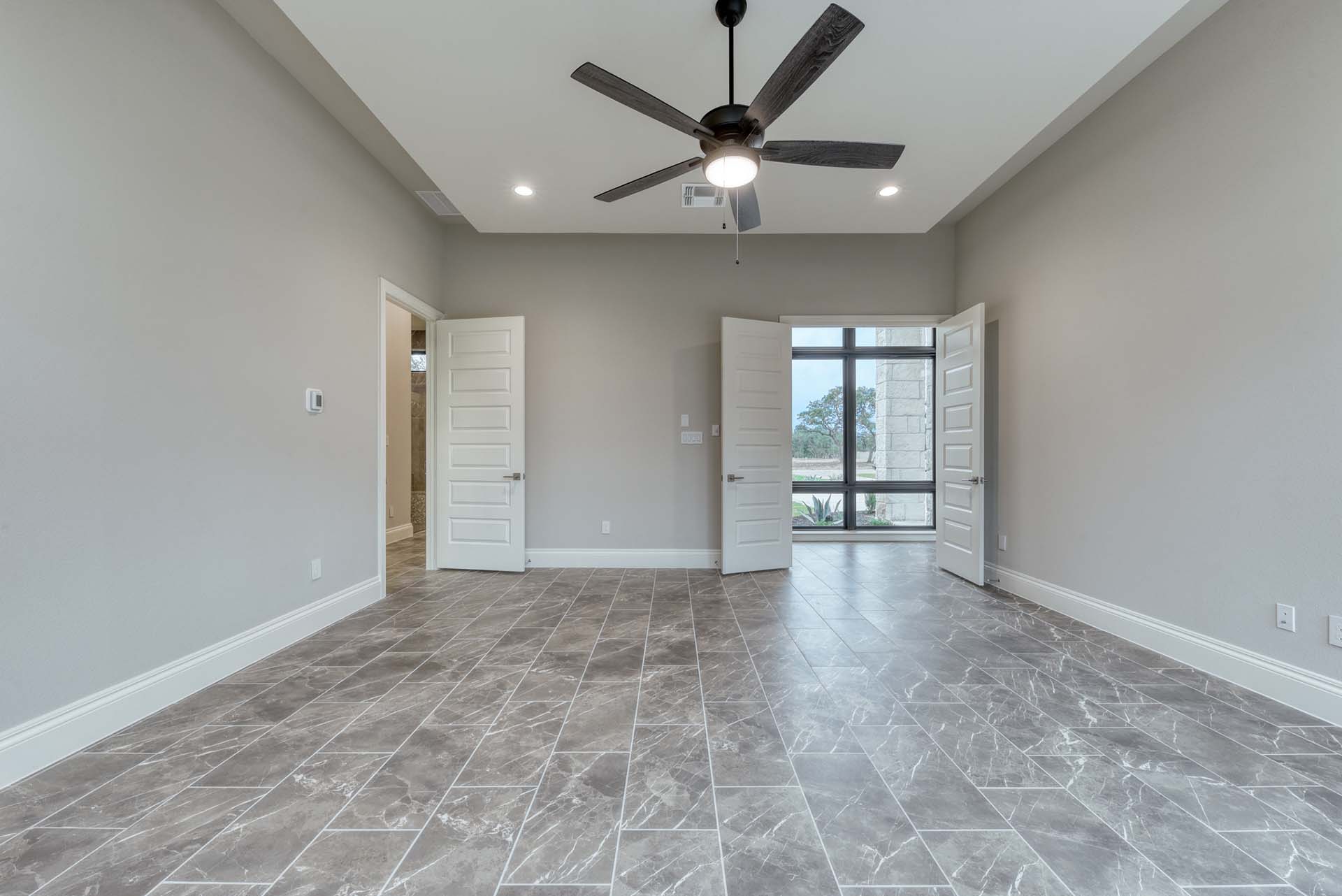 Empty room with tile flooring, ceiling fan.