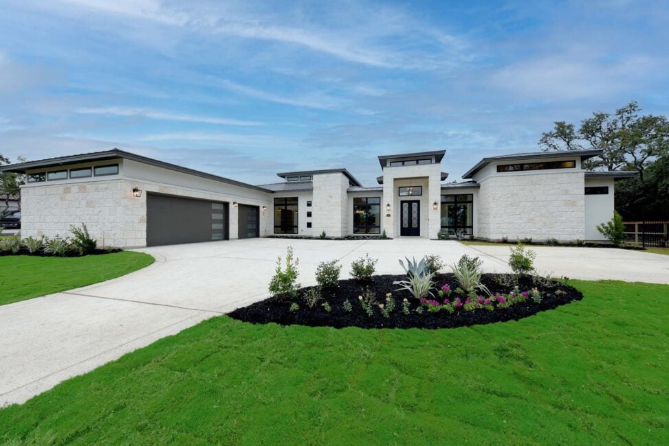 Modern house with large driveway and manicured lawn.