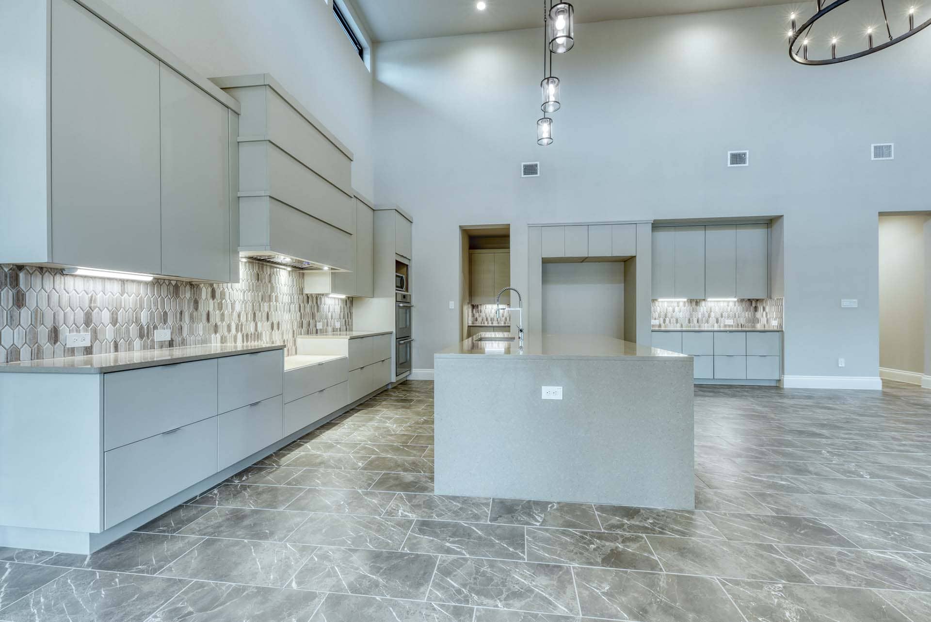 Spacious modern kitchen with minimalist design and tile backsplash.