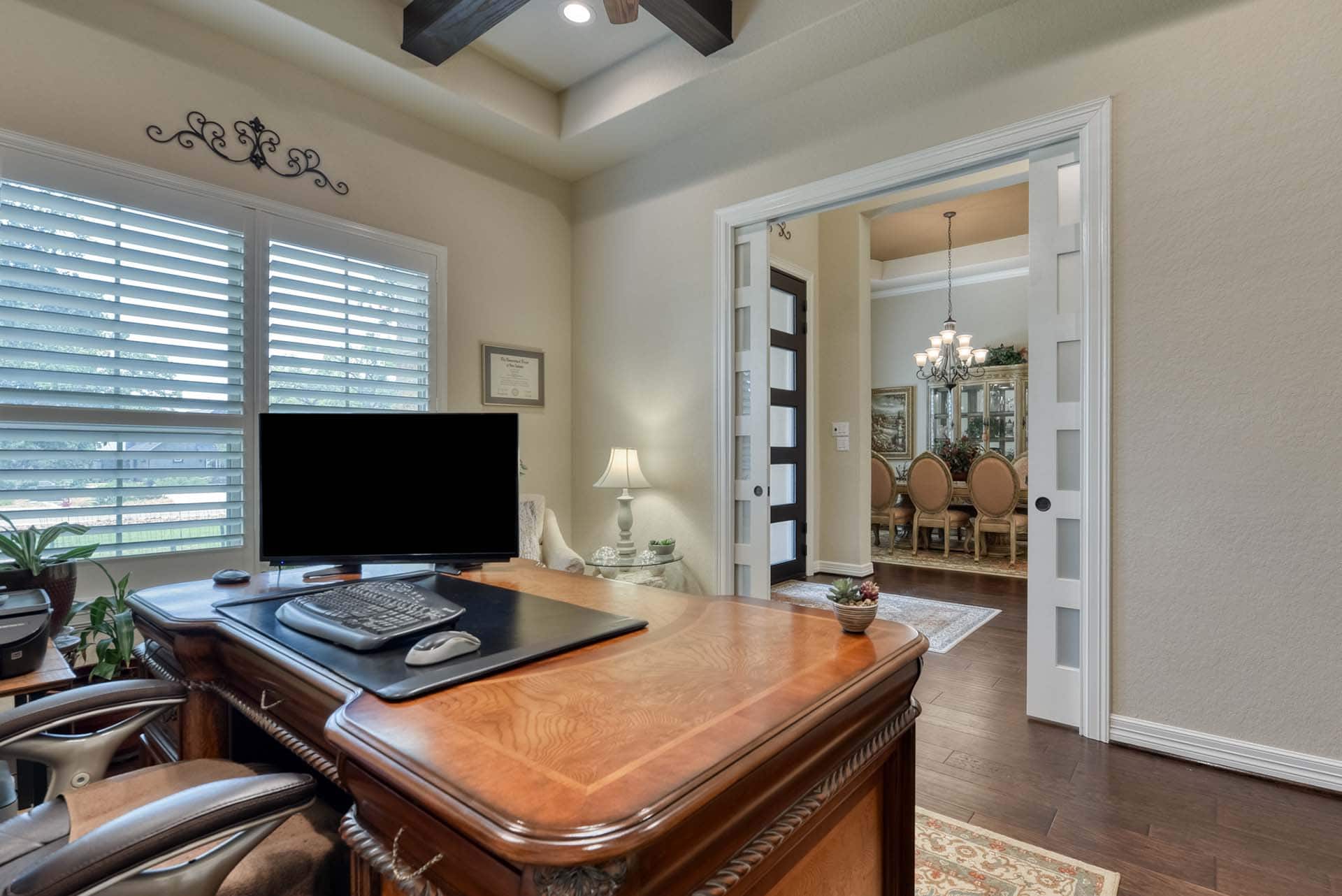 Home office with large wooden desk and dining area.
