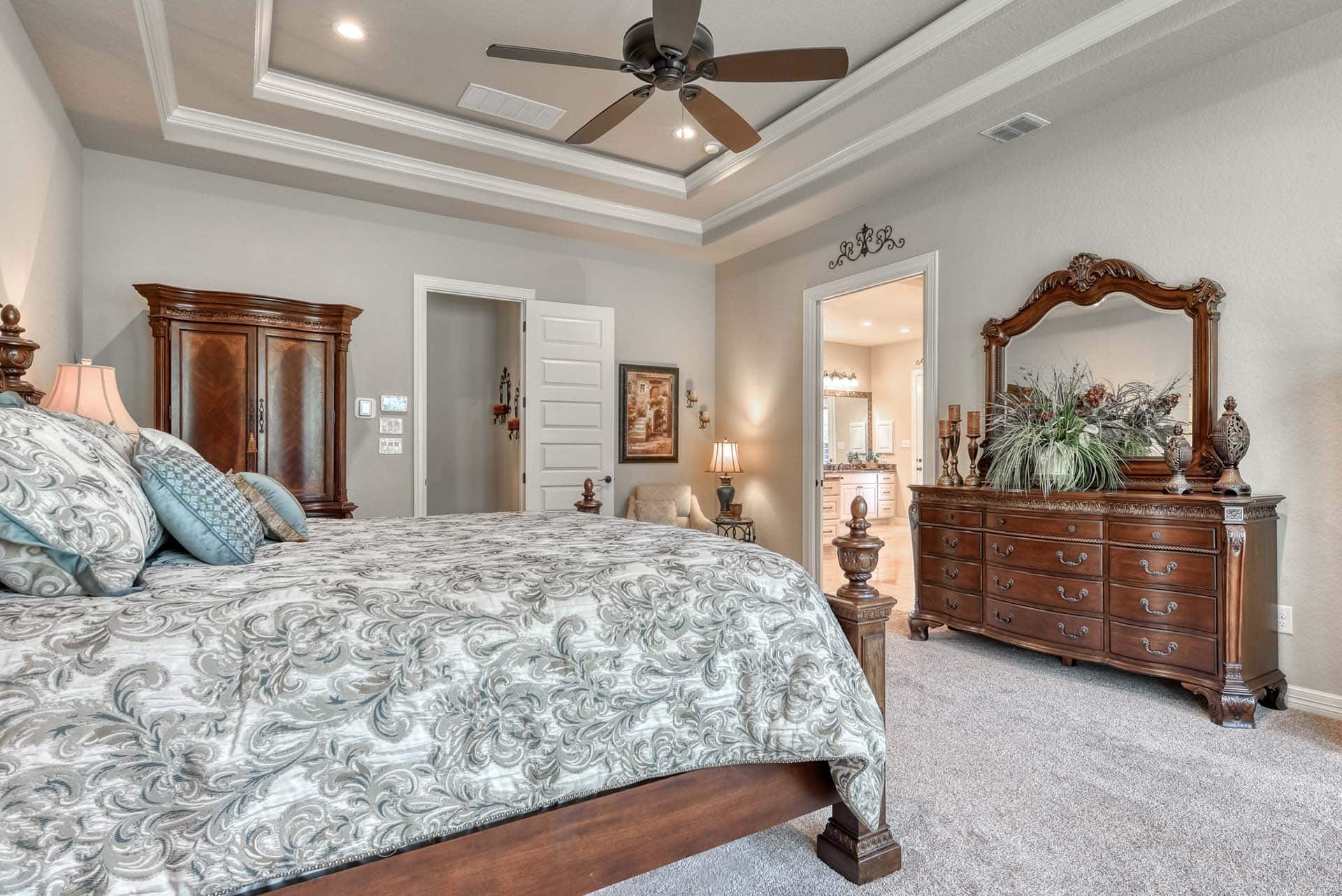 Elegant bedroom with wooden furniture and patterned bedding.