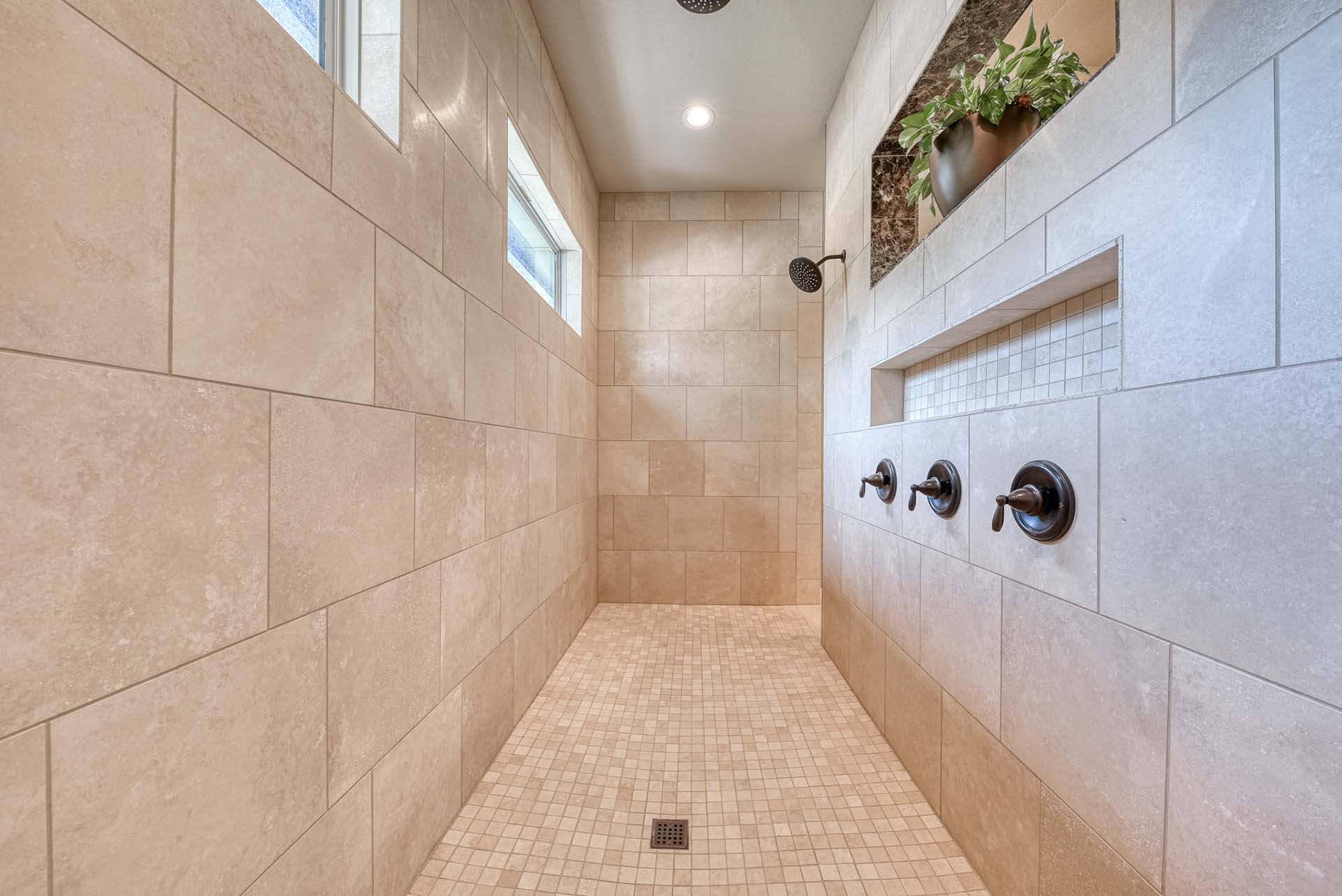 Modern spacious tiled shower with multiple showerheads.