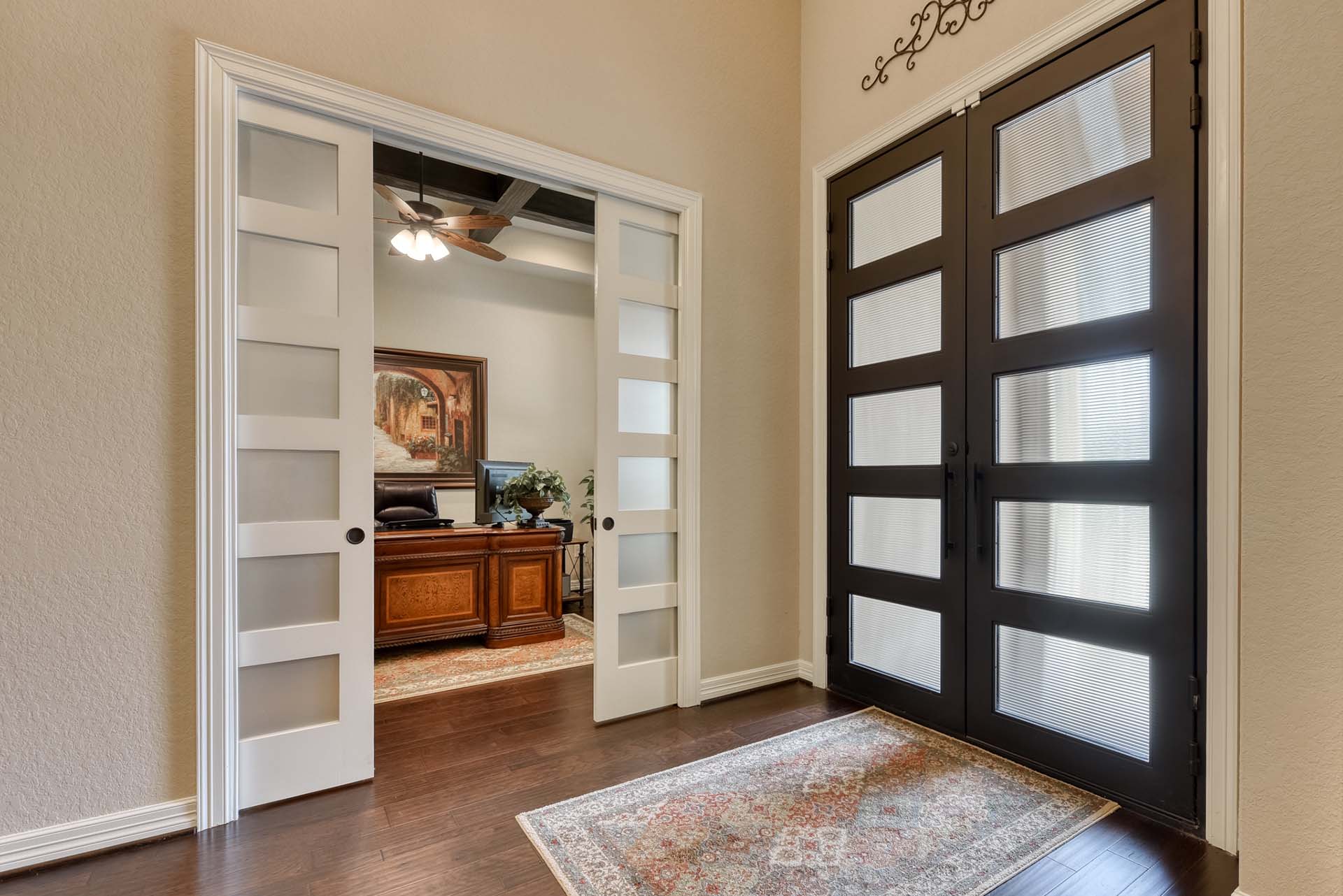 Elegant office with glass doors and wooden desk.