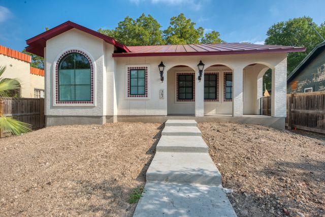 Charming white house with red roof and arch windows.