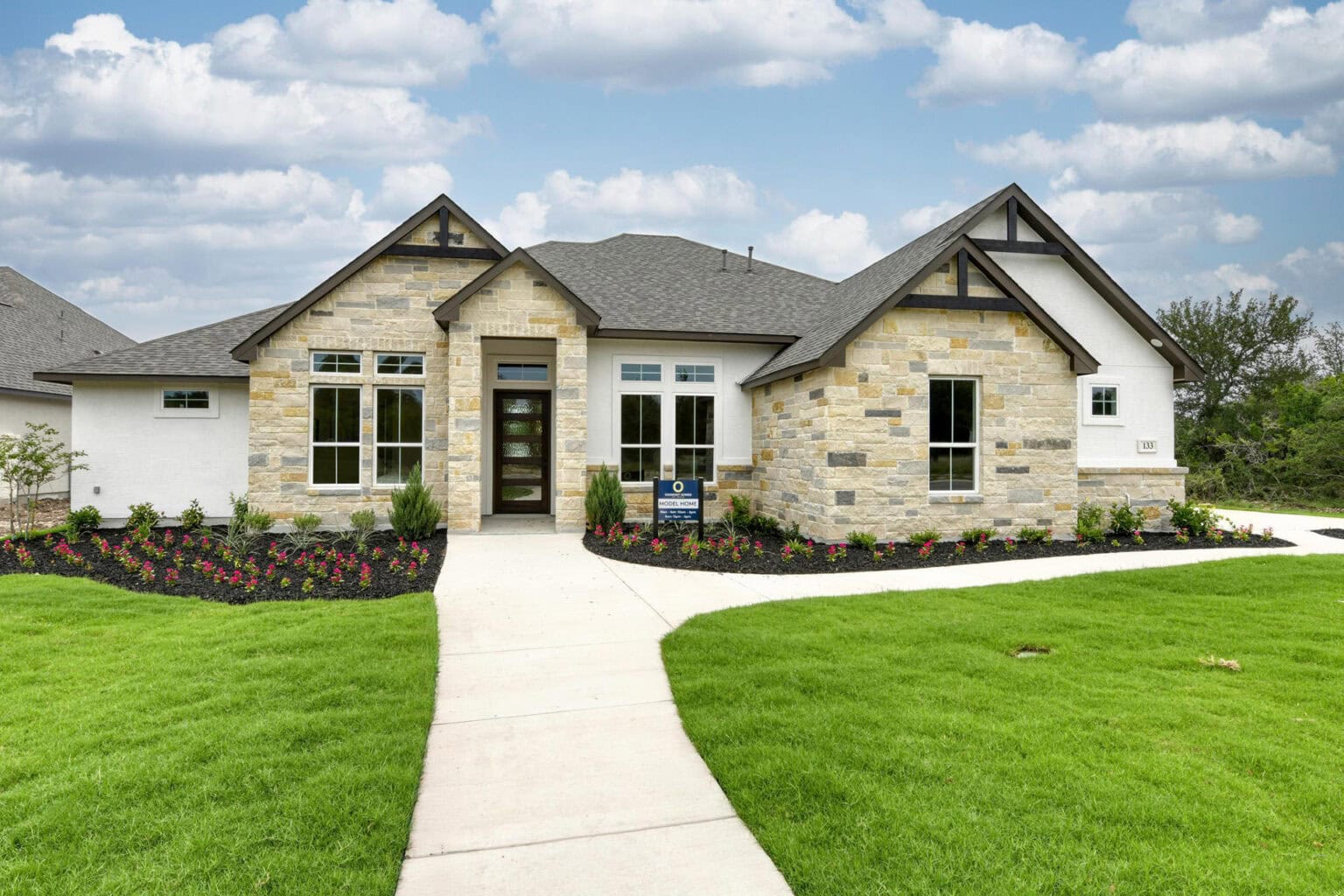 Modern stone house with landscaped front yard.