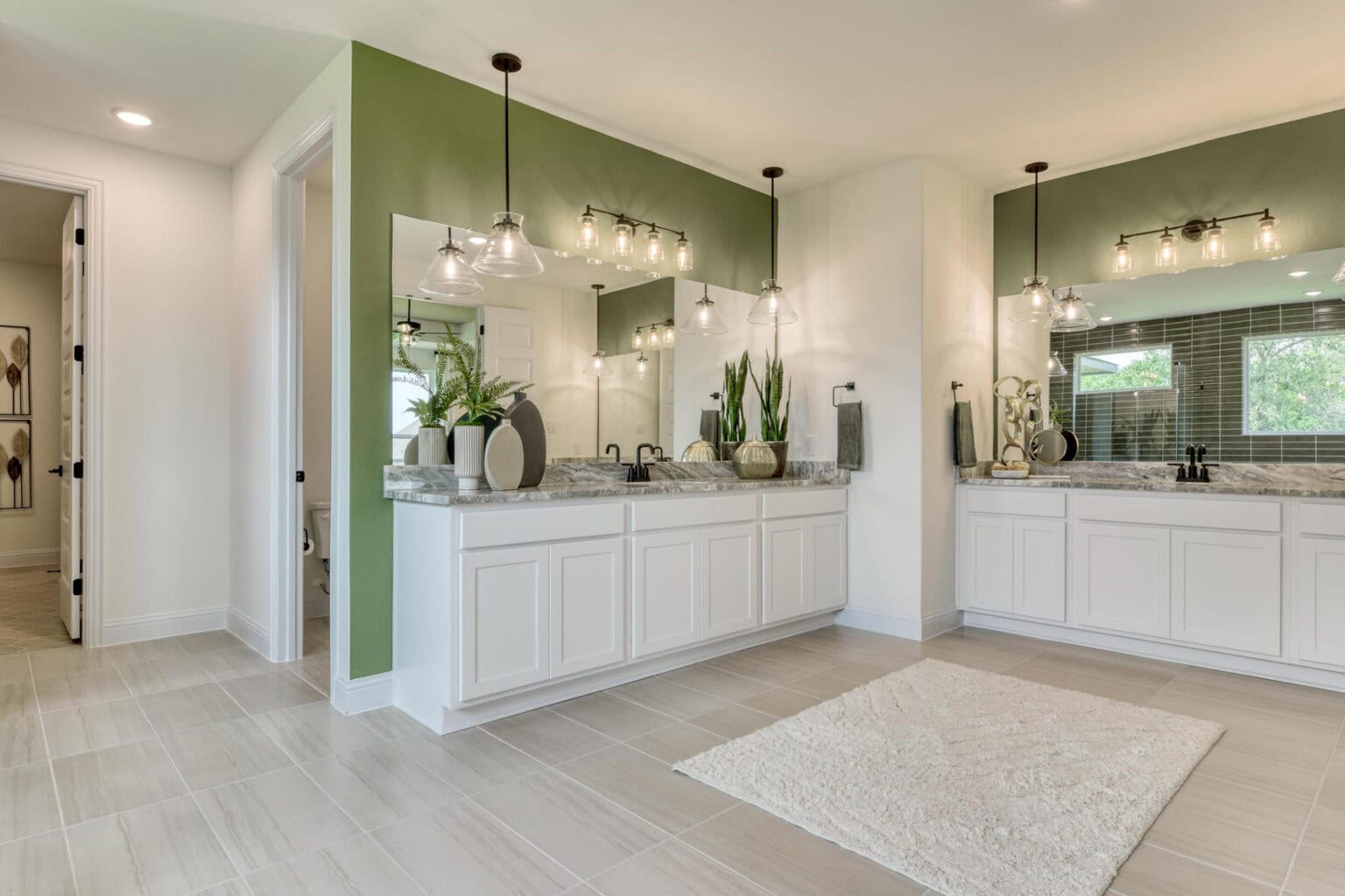 Modern bathroom with green accents and large mirrors.